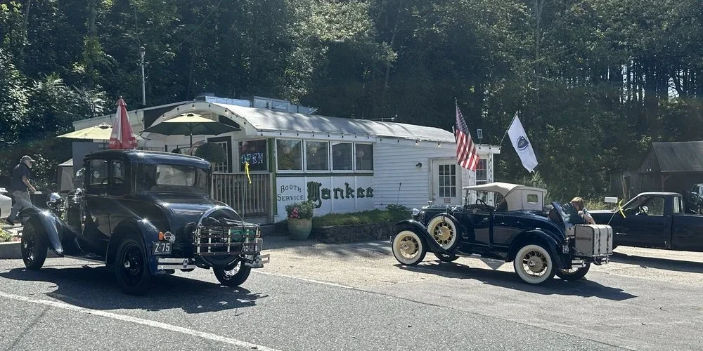 Yankee Diner, a white roadside diner car in Charlton, with two vintage Model-A Fords parked out front on a sunny day.