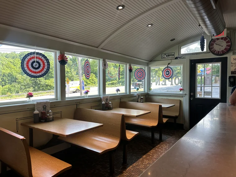 Wooden booths beside the windows at the far end of the diner, set with napkin holders and condiments.