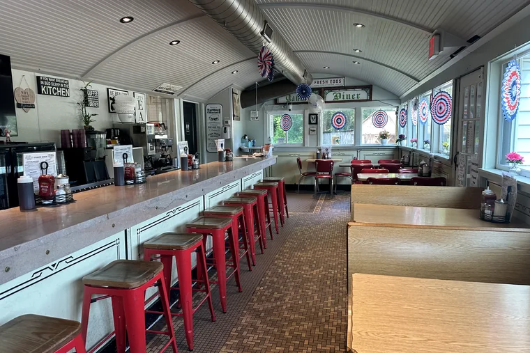 The full length of the counter with red stools, booths along the right and the barrel ceiling overhead.