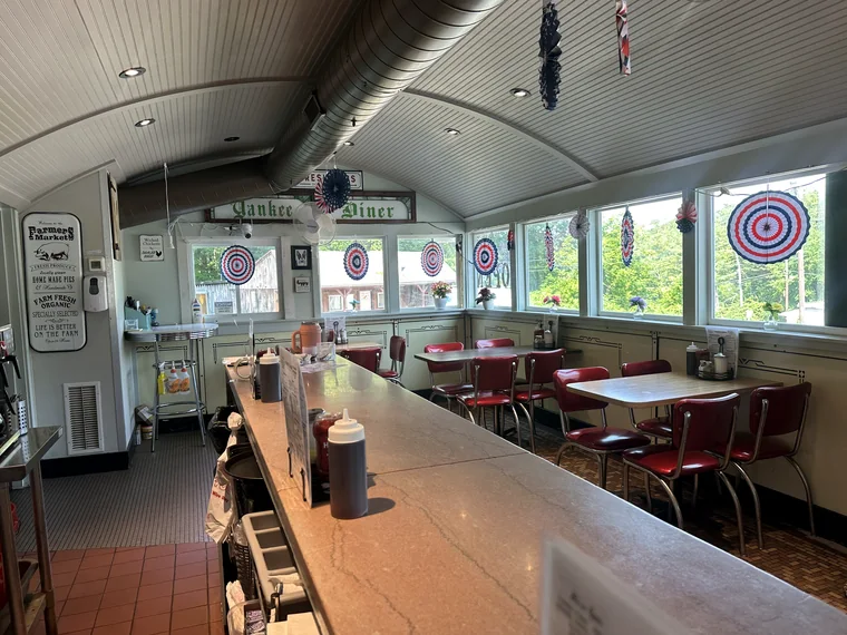 Looking back down the counter toward the far end of the car, where red chrome chairs sit at tables by the windows.